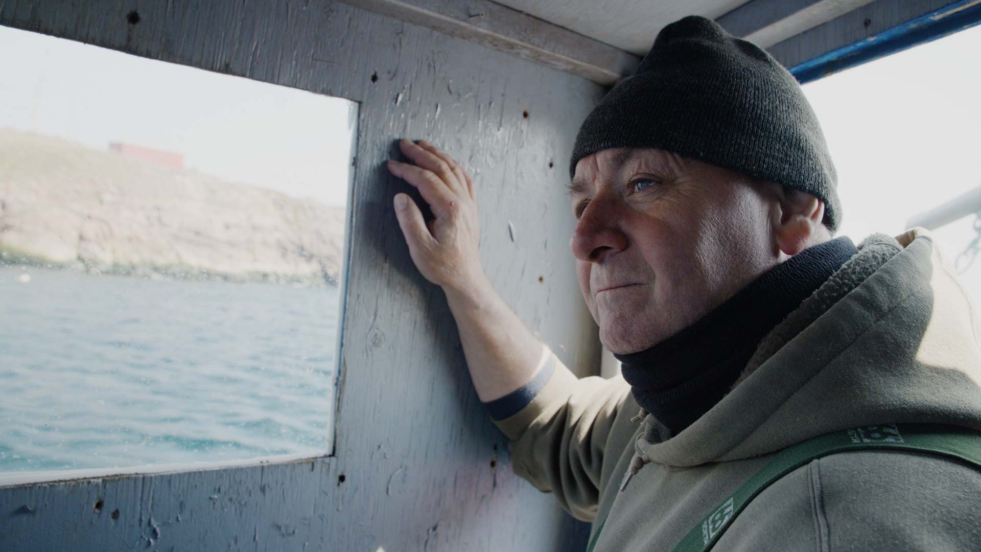 Doug Howlett dans la cabine de son bateau de pêche, manœuvrant dans la petite baie devant Petty Harbour, en route pour la pêche au homard.